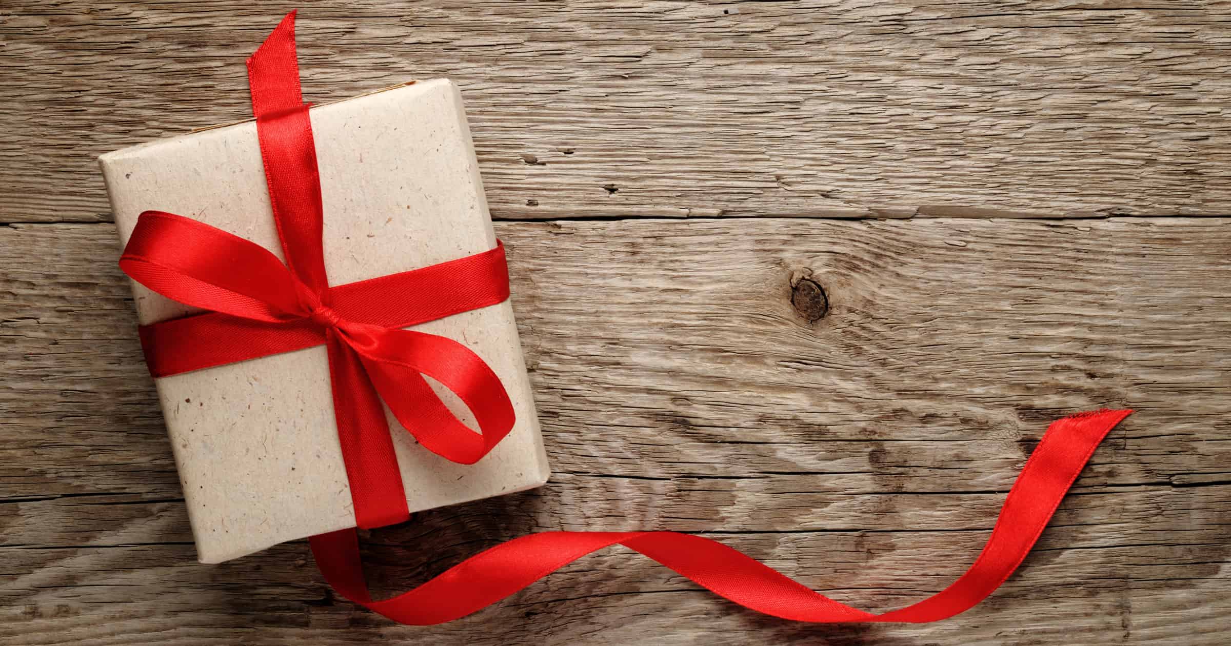 Gift box with red bow on wood background