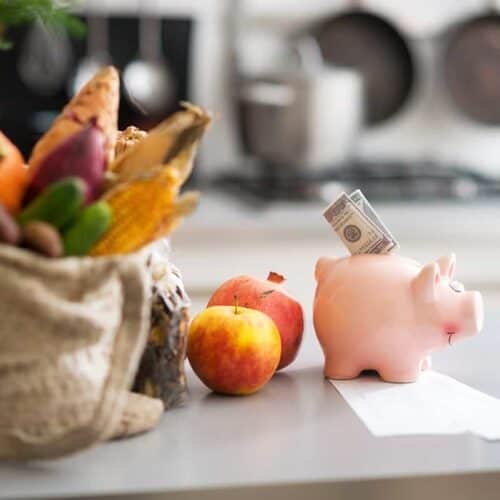 Image of a piggy bank on a counter with groceries next to it
